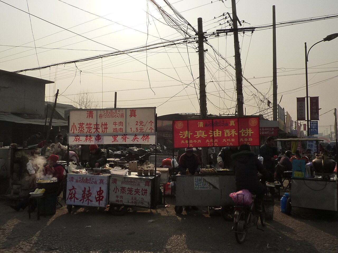 Street stalls selling halal snacks, with steam rising from cooking pots